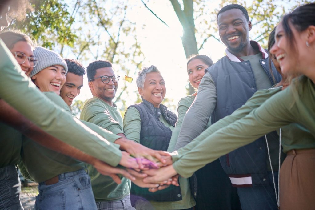 Team, motivation and friends in a huddle while hiking together in the forest or woods from below. F